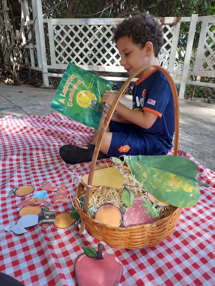 Criança lendo livro infantil bilíngue em atividade lúdica de inglês