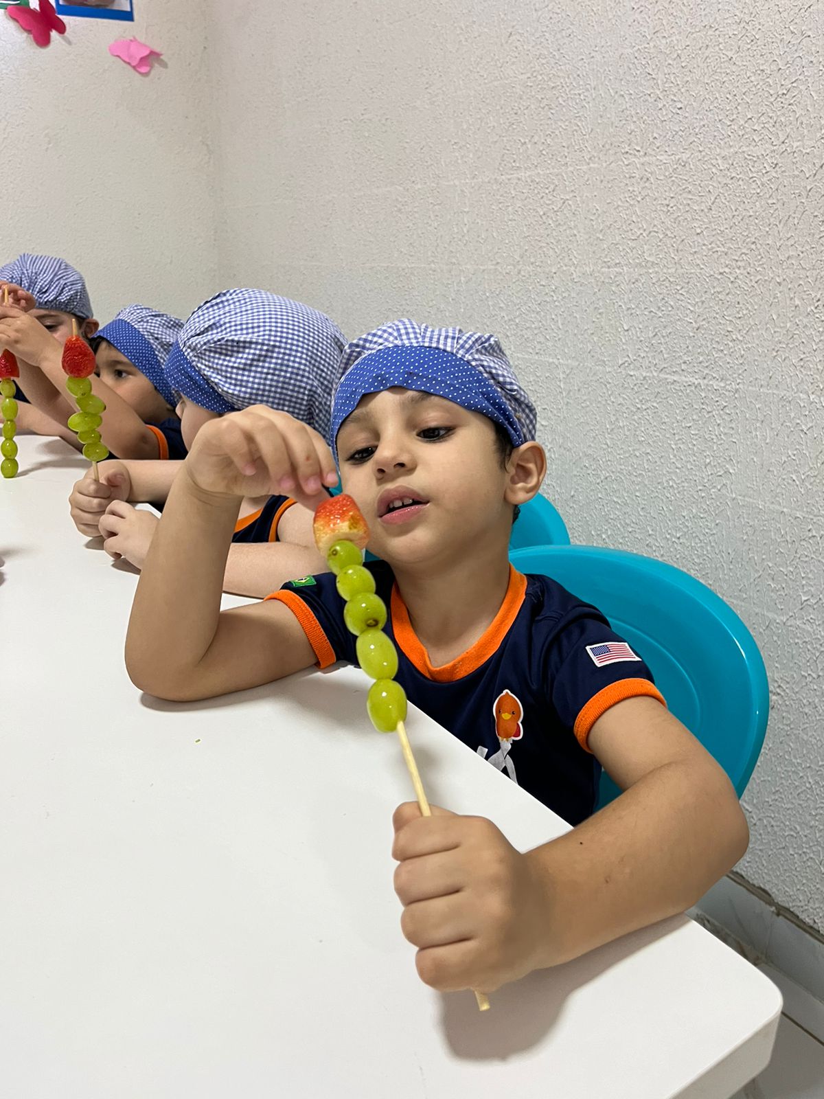 Aluno da Casa de Vó com espetinho de frutas em atividade de culinária saudável