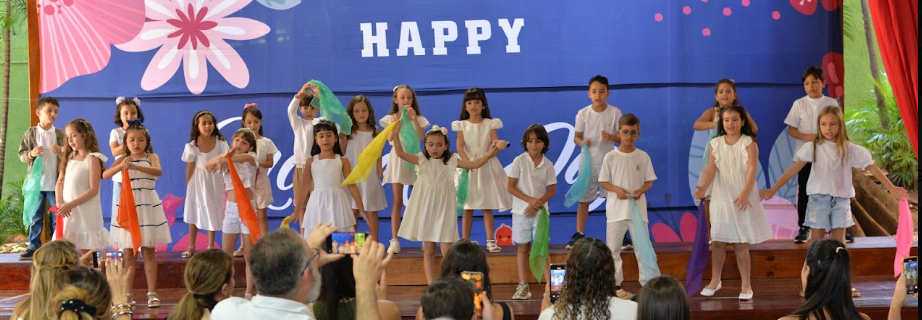 Criancas da Casa de Vo no palco em apresentacao especial de Dia das Maes com decoracao de flores