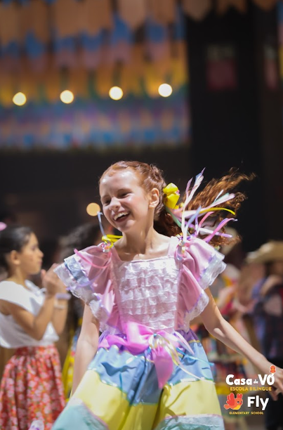 Aluna da Casa de Vo Fly dançando em traje tipico na Festa Junina da escola bilingue
